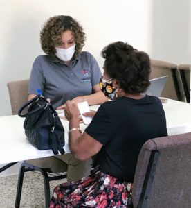 Two women sitting at a table wearing masks