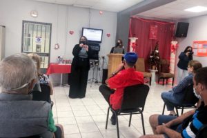 Two speakers address a room of people in chairs