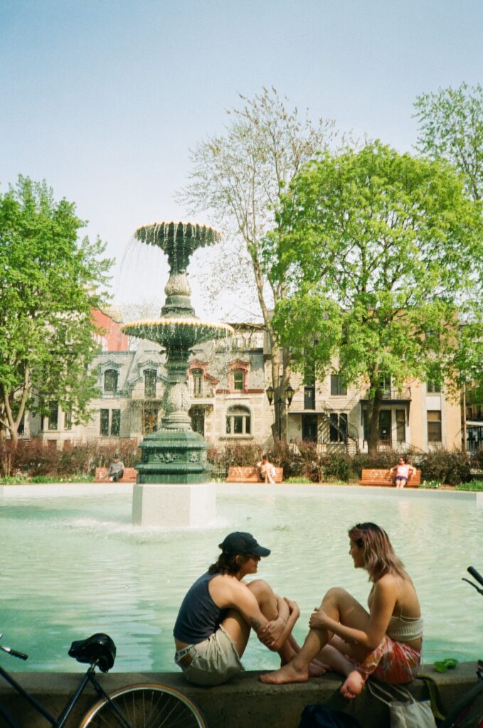 Two women sit facing each other at the edge of a large fountain