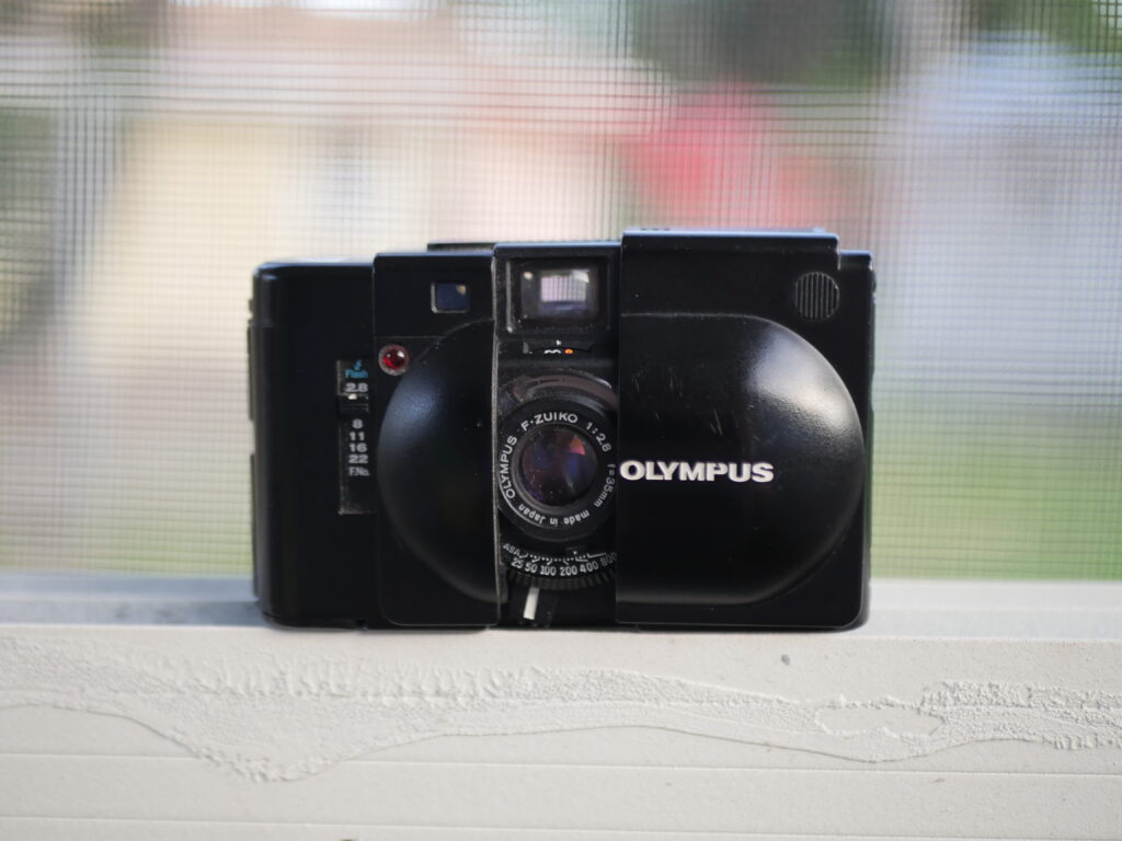 A black Olympus XA camera rests on a ledge